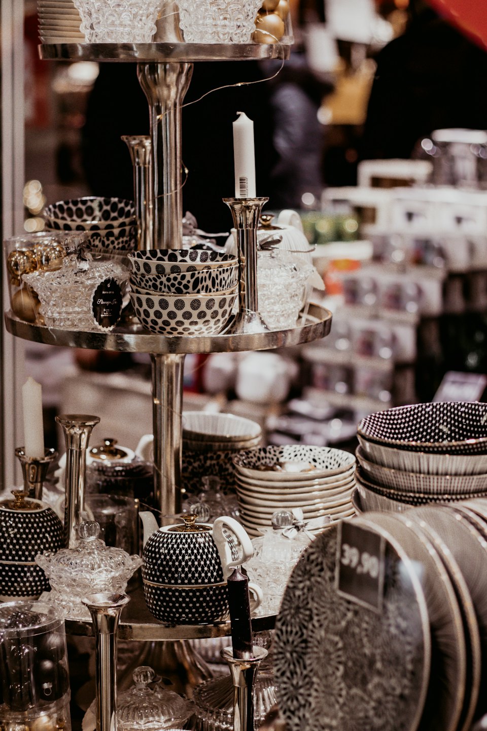 Espositore argentato con piatti in ceramica e oggetti decorativi per la casa.