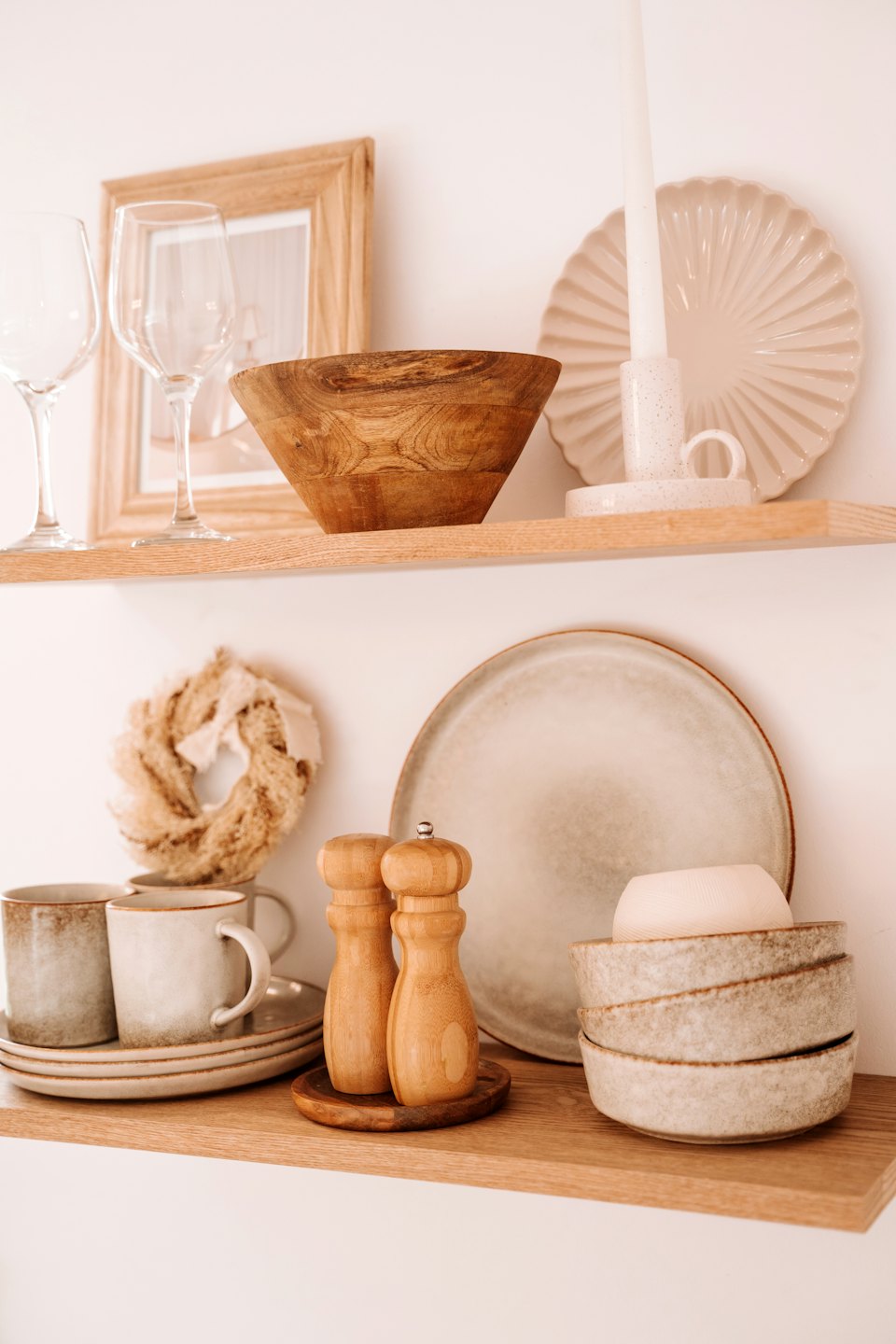 Utensili da cucina e decorazioni per la casa esposti su due mensole di legno a muro.
