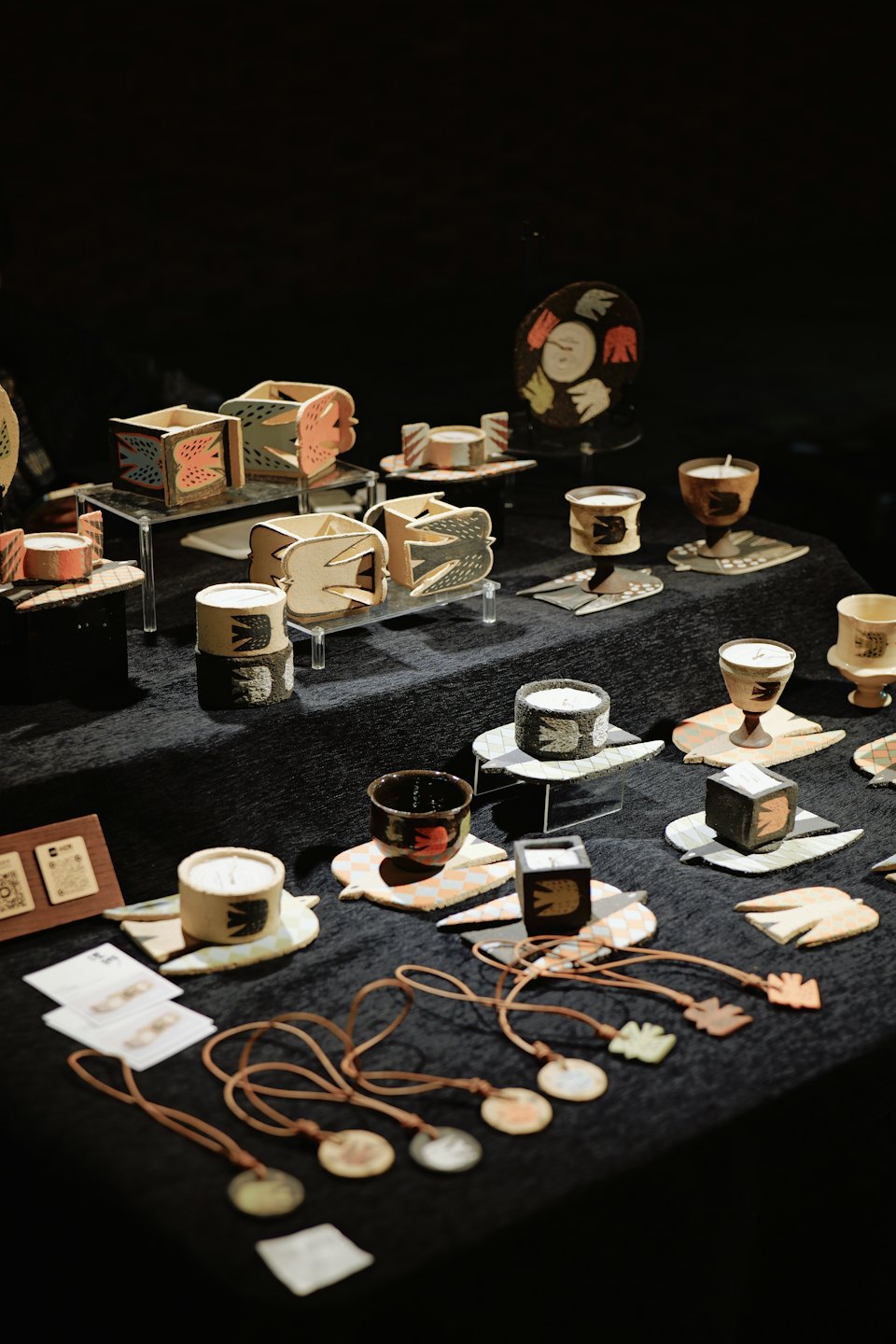 Uccelli e contenitori in ceramica artigianale su un tavolo espositivo scuro.