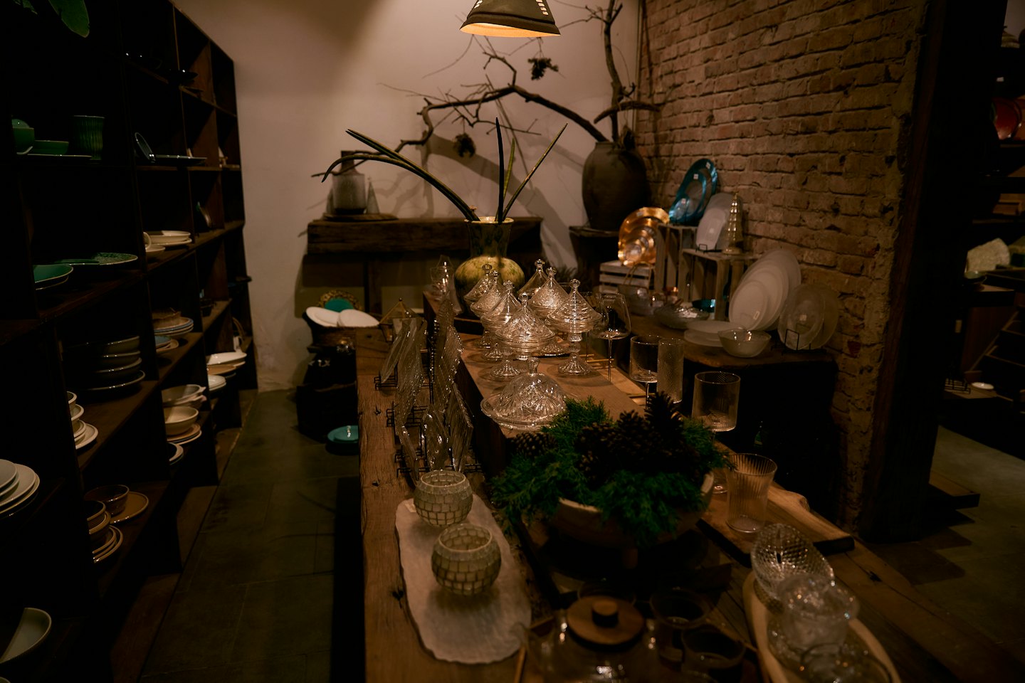 Ceramiche e vetri esposti su un tavolo rustico di legno in un negozio.