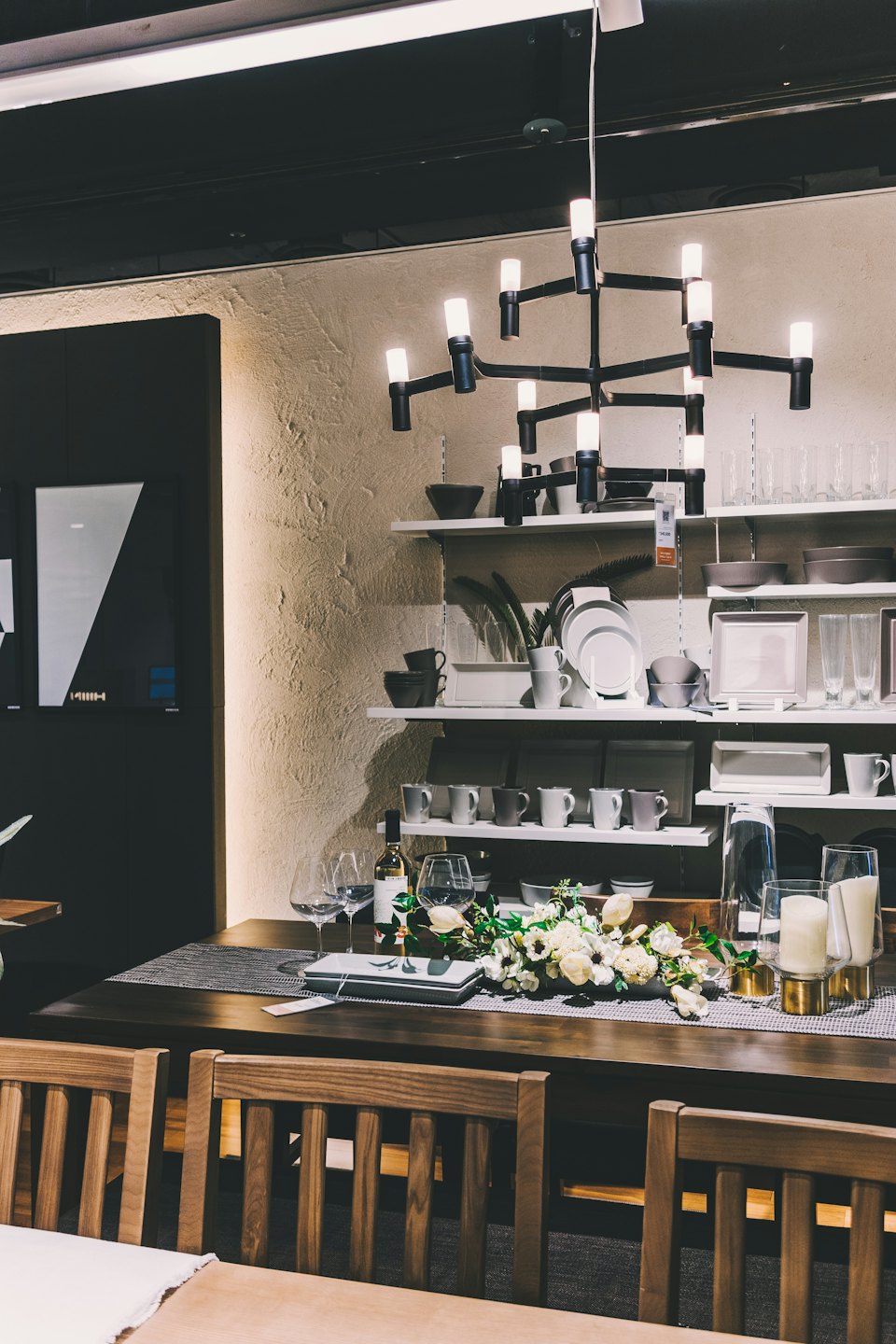 Un tavolo da pranzo apparecchiato con vino e fiori in uno showroom.