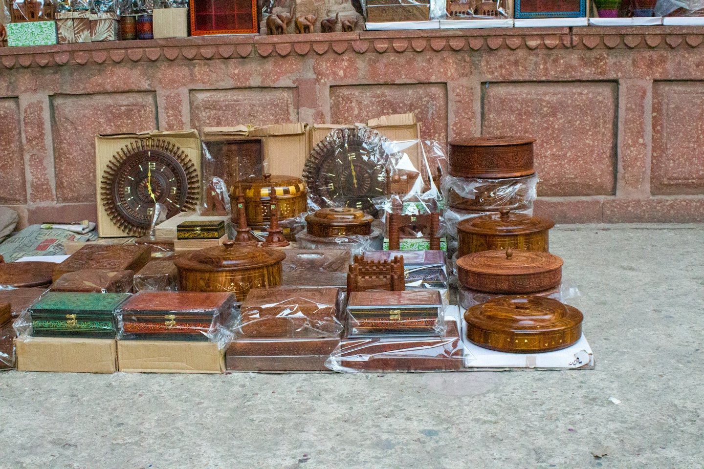 Orologi e scatole in legno artigianali esposti su una superficie di cemento.